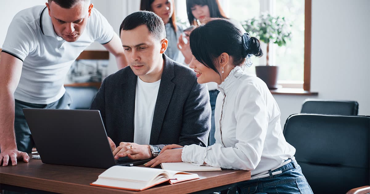 Drei Personen schauen am Arbeitstisch auf den selben Bildschirm